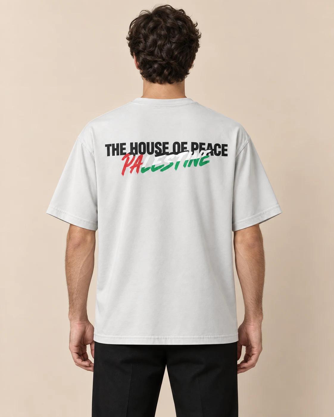 Homme de dos portant le tee H.O.P : « The House of Peace » en noir, « Palestine » aux couleurs du drapeau